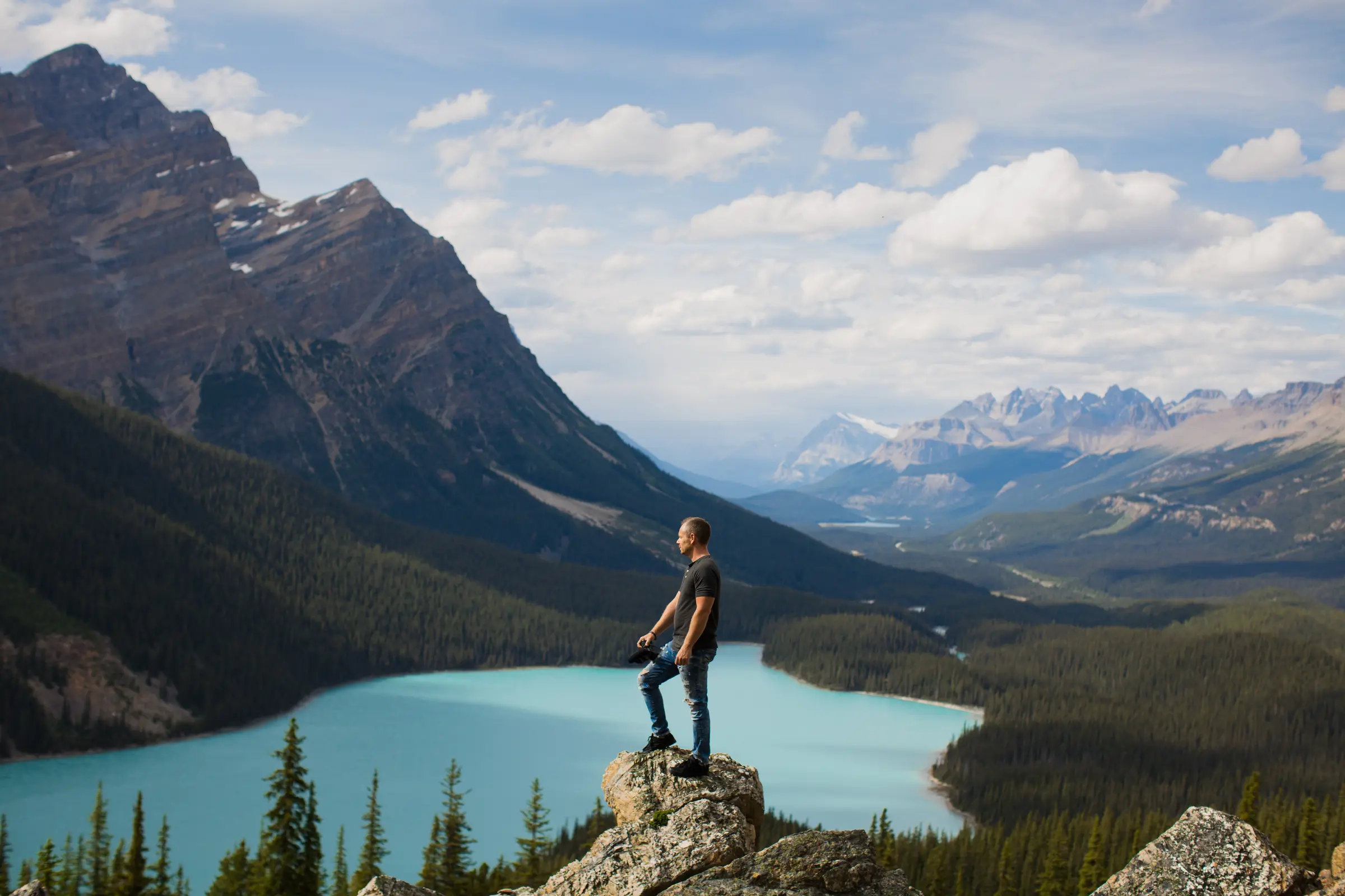 Chad Giesbrecht, owner of Pixel Pro Productions, standing on a rock above Peyto Lake in Banff National Park with a camera in hand